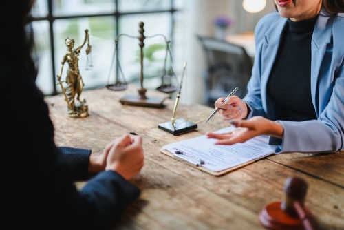 A personal injury lawyer speaking with a victim of a motor vehicle accident at a table with legal documents.