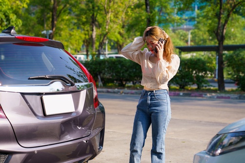A woman on the phone after a car accident to show what to say (and Not Say) to the other driver's insurance company after a Car accident.