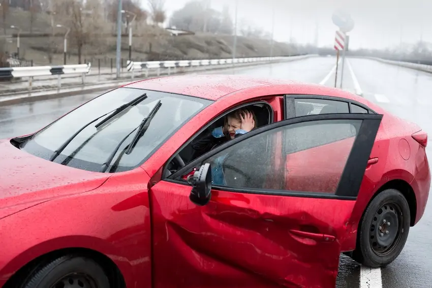 Car accident victim sitting in a damaged vehicle on a Georgia highway in the first moments after a serious crash
