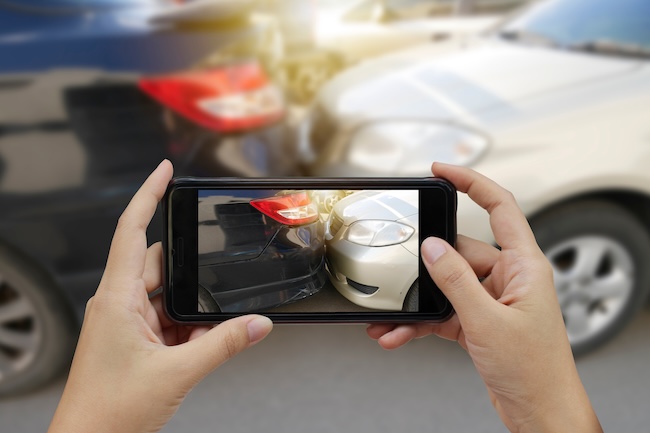 Car accident victim documenting crash scene damage with smartphone on Atlanta highway after serious collision