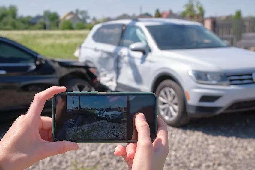 Car accident victim photographing vehicle damage and skid marks as evidence at Georgia crash scene