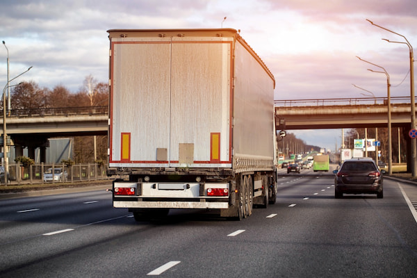 A semi-truck drives on an interstate highway.