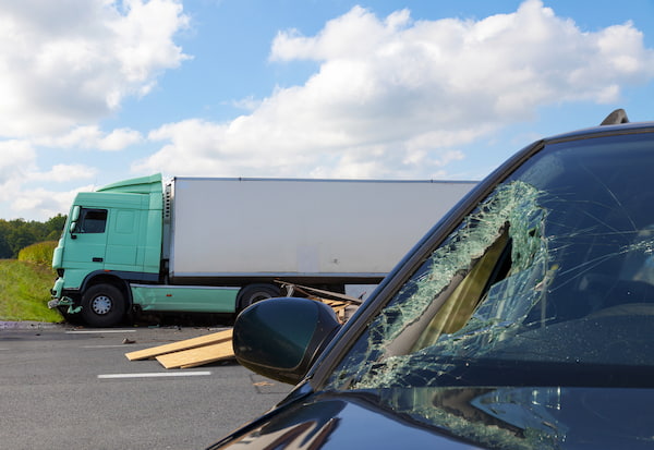 A crash scene with a car after a truck accident.